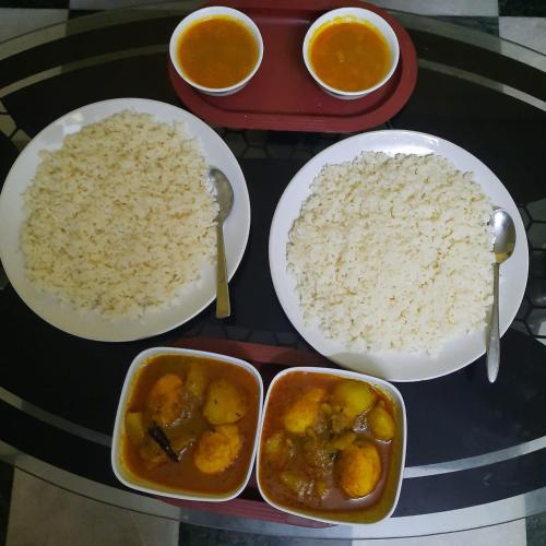 a table with plates of rice and bowls of food at Couple Friendly Rooms in kolkata