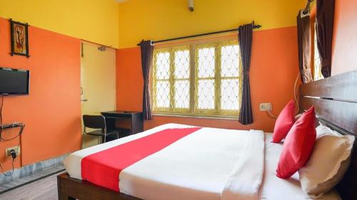 a bedroom with orange walls and a bed with red pillows at Couple Friendly Rooms in kolkata