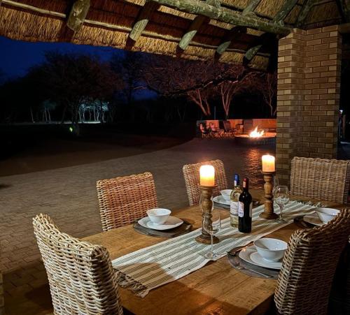 a wooden table with chairs and wine bottles on it at Camel Creek Safari Lodge in Thabazimbi