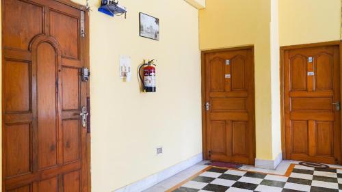 a hallway with two wooden doors and a checkered floor at Couple Friendly Rooms in kolkata