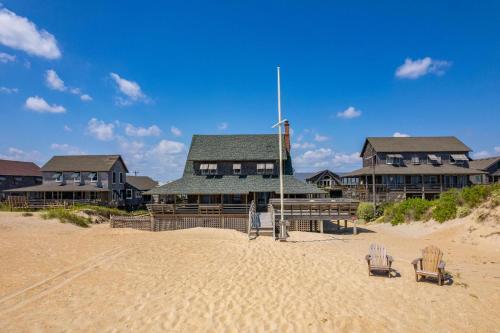 ein Haus am Strand mit zwei Stühlen im Sand in der Unterkunft NH315 Serenity by the Sea in Nags Head