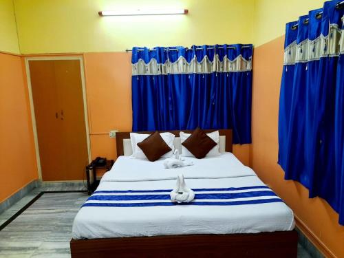 a bedroom with a bed with blue curtains at Couple Friendly Rooms in kolkata