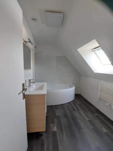 La salle de bains est pourvue d'une baignoire, d'un lavabo et d'une lucarne. dans l'établissement Maison Bretonne avec piscine, à Marzan