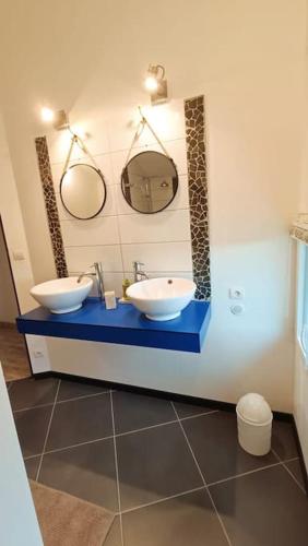une salle de bain avec deux lavabos et deux miroirs dans l'établissement Maison, à Neuvic