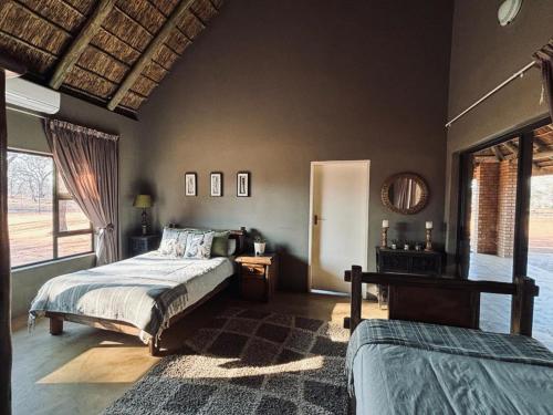 a bedroom with two beds and a large window at Camel Creek Safari Lodge in Thabazimbi