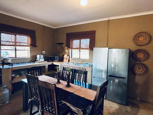 a kitchen with a table with chairs and a refrigerator at Camel Creek Safari Lodge in Thabazimbi
