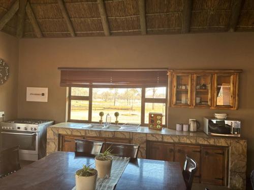 a kitchen with a table and a sink and a window at Camel Creek Safari Lodge in Thabazimbi