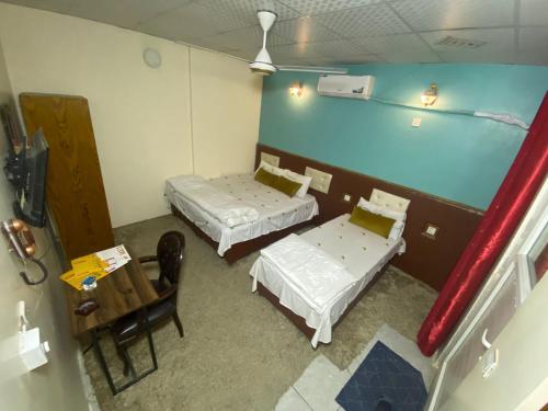 a room with two beds and a table in it at فندق عسل - Asal Hotel in Baghdad