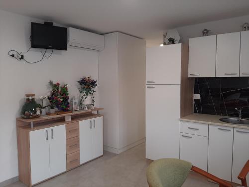 a kitchen with white cabinets and a tv on the wall at Apartmani Show Zagreb in Zagreb