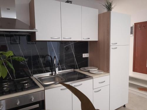 a kitchen with white cabinets and a sink at Apartmani Show Zagreb in Zagreb
