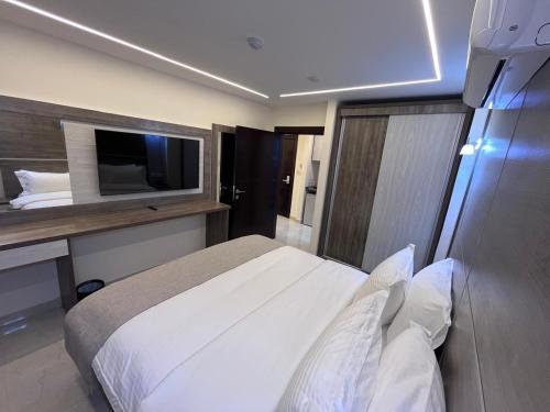 a bedroom with a white bed and a television at Golden Light Aqaba Hotel فندق جولدن لايت العقبة in Aqaba