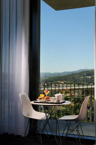 a table with a plate of food on it in front of a window at Open Village Sports Hotel & Spa Club in Guimarães
