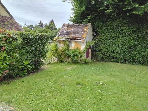 a small house in a yard next to a hedge at Maison familiale dans le Perche in Val-au-Perche