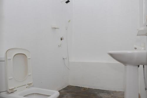 a white bathroom with a toilet and a sink at Emerald Bay in Arugam Bay