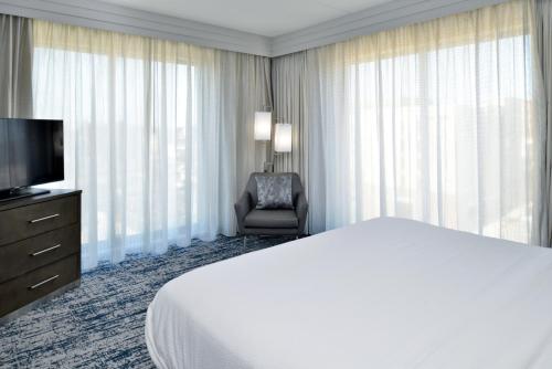 a hotel room with a bed and a chair and a television at Courtyard by Marriott Wilmington Downtown/Historic District in Wilmington