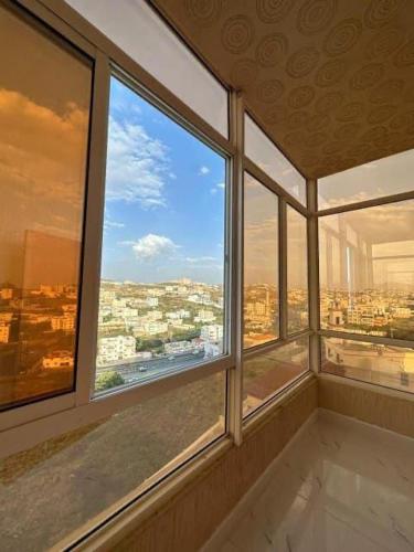 a room with three windows with a view of a city at منازل الباحة للشقق الفندقية in Al ‘Āmirah