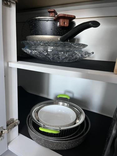a frying pan and plates on a shelf in a kitchen at Resa Apartment in Vlorë