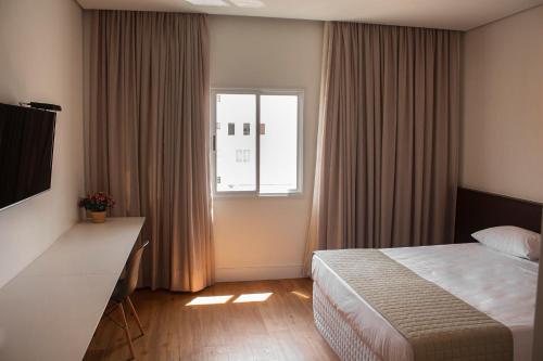 a hotel room with a bed and a window at Vip Hotel in Jaú