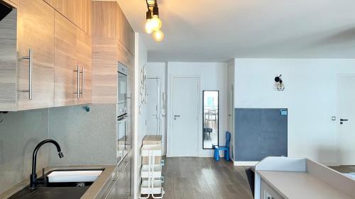 une cuisine avec des comptoirs blancs et des armoires en bois dans l'établissement 129 - Splendeur Confort et Modernité, Terrasse au Cœur de Paris, à Paris