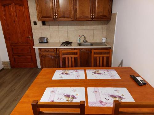 a kitchen with a wooden table with two mats on it at Hanol Apartmanház Balatonlelle in Balatonlelle