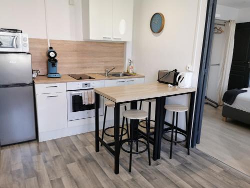 a kitchen with a table and stools in a room at Bel appartement en face de la pépinere de Nancy Stanislas in Nancy