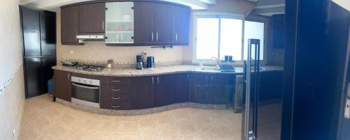 a kitchen with dark blue cabinets and a refrigerator at Grand appartement ensoleillé, suite parentale, 2 salons, 2 salles de bains, 2piscines, stationnement privé, à 750m de la plage Mimosa in Pont Blondin