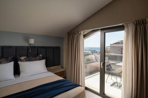 a bedroom with a bed and a balcony with a view at Endless Blue Luxury Suites in Nikiti