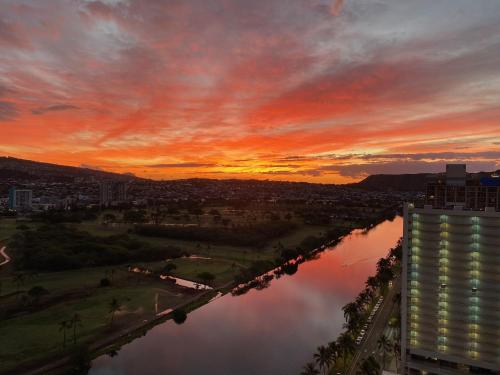 a view of a river at sunset with a building at Amazing View Waikiki Beach 28th Floor 1BR Family and Group Condo in Honolulu