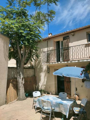 un patio avec une table, des chaises et un parasol dans l'établissement Corniche Bleue à 3 mn à pied de la plage, à Sète