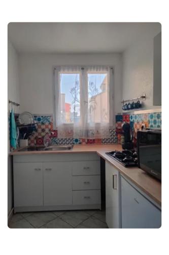 une cuisine avec un évier et une fenêtre dans l'établissement Corniche Bleue à 3 mn à pied de la plage, à Sète