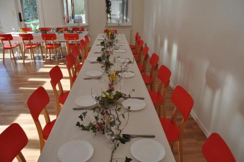 a long table in a room with red chairs at långstorp in Höör
