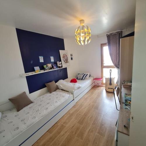 un salon avec un canapé et un mur bleu dans l'établissement Appart Cosy Family near JO2024, à Saint-Denis