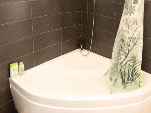 a bath tub with a shower curtain in a bathroom at Jungle appartement lumineux plein centre in Boulogne-sur-Mer