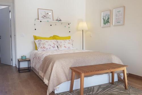 a bedroom with a bed with a wooden bench on it at Cute Home in Tavira