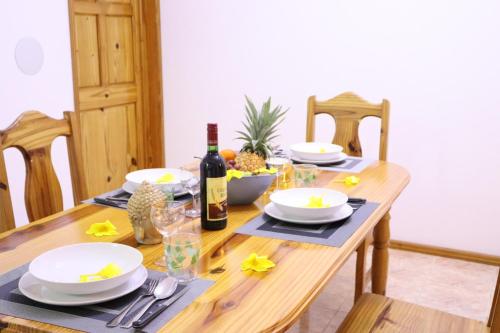 a wooden table with white dishes and a bottle of wine at Sunset view Suite in Trou dʼ Eau Douce