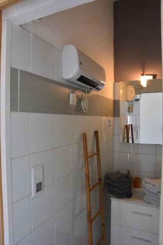 une cuisine avec un mur carrelé blanc et une échelle dans l'établissement Maisonnette en Provence climatisée, wifi, parking, à Arles