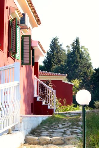 a red house with a white fence next to a walkway at Mediterranean Blue in Kavos