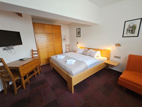a bedroom with a bed and a desk and a television at Ski&Bike Nassfeld Apartments in Hermagor