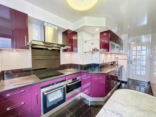 - une cuisine avec des placards violets et une cuisinière dans l'établissement 115 - Paris, Appartement luxueux spacieux avec vue panoramique, à Paris