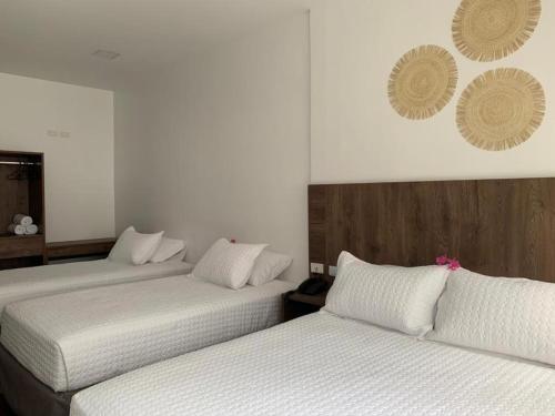 two beds in a hotel room with white sheets at Hotel La Mar Playas in Playas