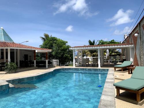 a swimming pool with chairs and a gazebo at Hotel La Mar Playas in Playas