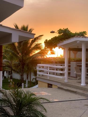 a sunset over a resort with palm trees and a building at Hotel La Mar Playas in Playas