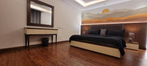 a bedroom with a bed and a desk and a mirror at Goldcrest Apartments in Lahore