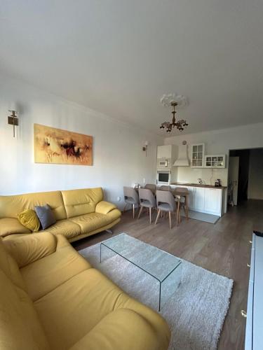 a living room with a yellow couch and a kitchen at Macedonia Square Apartment in Skopje