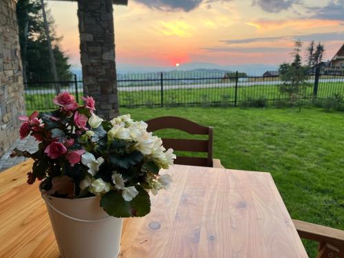 a vase of flowers sitting on a table with the sunset at apartamenty 1006 m n p m in Bustryk