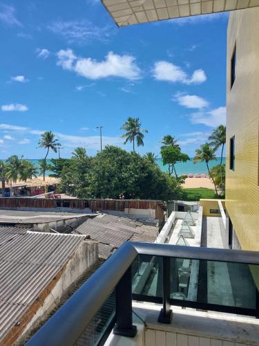 a balcony with a view of the beach and palm trees at Mar do Cabo Branco Residence in João Pessoa