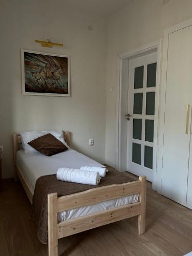 a bedroom with a bed with a wooden bench and a door at Macedonia Square Apartment in Skopje