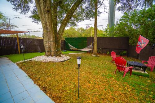 a yard with red chairs and a table and a tree at Stylish Urban Haven, Cozy, Central in Lutz