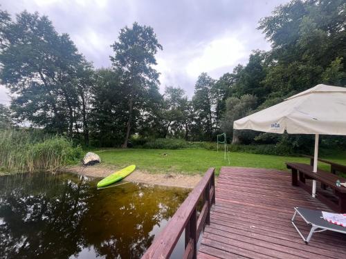 un ponte con un tavolo e un ombrellone accanto a uno stagno di Dworek Biesiadny a Radzewice