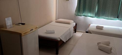 a small room with two beds and a table at Hotel San Conrado in Salinópolis